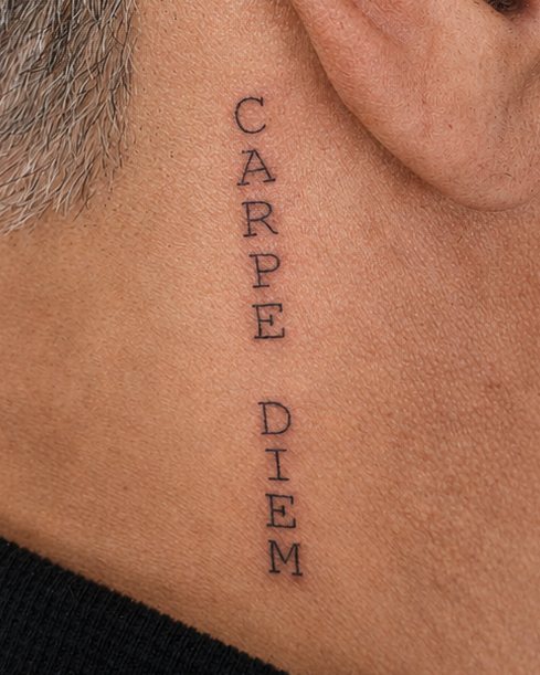 Carpe Diem em letras finas na lateral do pescoço
